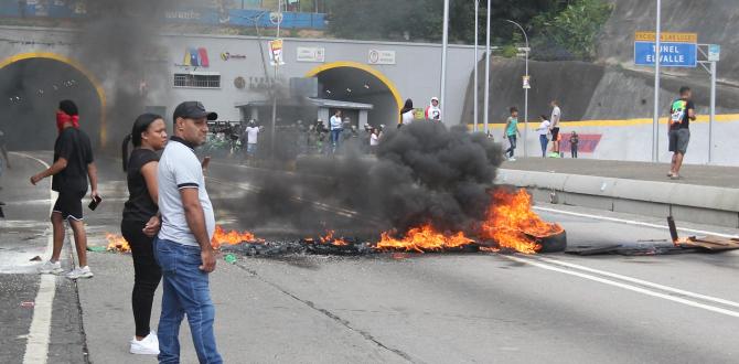 Personas observan la vía bloqueada por neumáticos en Caracas.