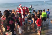 Decenas de niños recibieron a Papá Noel en la orilla de la playa, una vez que llegó en moto acuática.