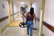 Una mujer lleva un ventilador para el cuarto del HTMC donde está su paciente.