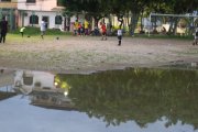 Niños practicando fútbol en la cancha inundada y repleta de mosquitos.