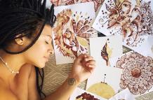 Jasmine Carter junto a algunas de sus pinturas hechas con su período.