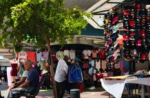 Un vendedor informal ofrece ropa justo frente a locales establecidos dedicados al mismo rubro.