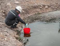 Una persona recoge el agua contaminada del río Daule.
