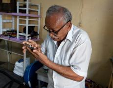 Víctor Guarín mientras mira su teléfono con ayuda de unos lentes, pero con una escasa visión.