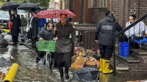 Peatones caminan por una vereda inundada el viernes 29 de septiembre de 2023, en el distrito de Brooklyn en Nueva York.
