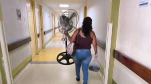 Una mujer lleva un ventilador para el cuarto del HTMC donde está su paciente.