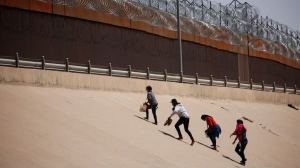 Referencial. Migrantes intentan cruzar el muro para ir a Estados Unidos.