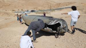 Curiosos observan los restos de un misil balístico en el desierto, tras un ataque de Irán contra Israel, cerca de la ciudad sureña de Arad.