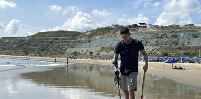 Bryan Zambrano mientras recorre la playa de San Mateo, en Manta, en busca de objetos de valor que quedan enterrados tras la marea.