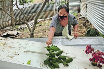 Con la rama de un árbol, Elsa Bonilla Ponce limpia la improvisada tumba de su progenitora, Ángela Ponce Merchán.