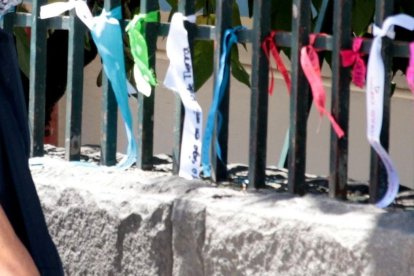 Algunos familiares que esperan noticias de sus parientes en las afueras del hospital se dan una vuelta por las rejas donde están los lazos.