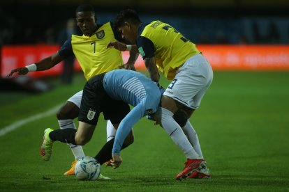 Agustín Álvarez de Uruguay disputa el balón con Pervis Estupiñán (i) y Piero Hincapie (d) de Ecuador.