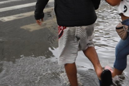 Un par de muchachos intentaban cruzar la avenida Quito sin mojarse.
