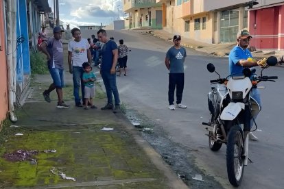 Vecinos del barrio El Rocío observan la escena acordonada por la Policía tras el ataque armado que dejó una mujer fallecida y otra herida.