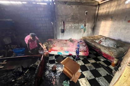 Una mujer revisa entre los restos calcinados de su vivienda, buscando entre las cenizas lo poco que el incendio dejó en pie.
