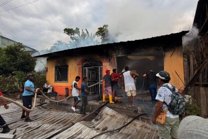 Vecinos de la parroquia Montalvo intentan sofocar las llamas con mangueras mientras un incendio consume una vivienda en Rioverde, Esmeraldas.