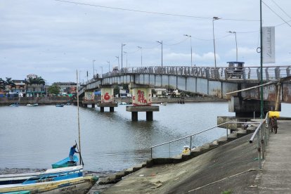 Puente sobre el estuario de Muisne, donde conviven el tránsito urbano, las embarcaciones artesanales y la vida cotidiana de la ribera.