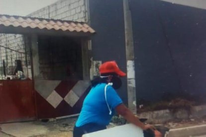 Carolina Espinoza recorre el cantón Playas en su bicicleta con un pizarrón al hombro.