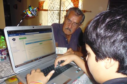 Alfonso Idrovo comprueba, con ayuda de su nieto, los datos que se revelan en la pantalla de la computadora, en la página del Isspol.