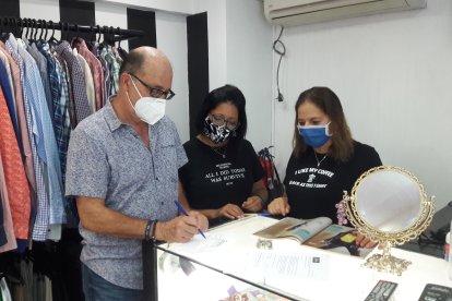 Juan firmando su contrato por las piezas que entrega en el local de ropa usada.