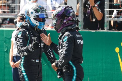 Valtteri Bottas (i) recibe la felicitación de su compañero de escudería, Lewis Hamilton (d), tras ganar la 'pole' del Gran Premio de Austria.