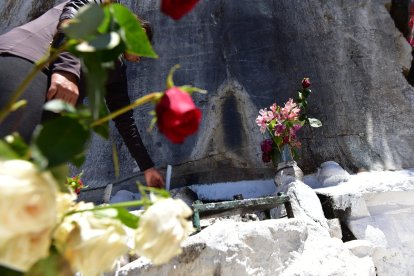 El manto de Virgen se encuentra sobre un altar rodeado de velas y flores.