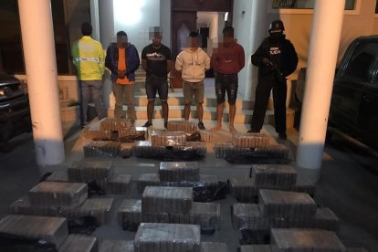 Los detenidos junto a los paquetes de droga decomisados.