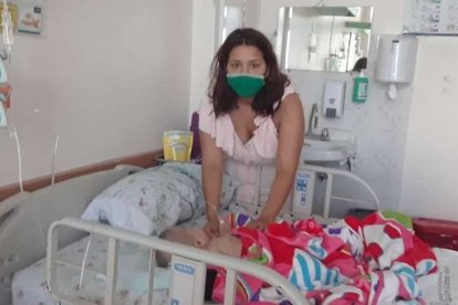 Jéssica está junto a la cama de hospital en la que duerme su bebé de tres meses.