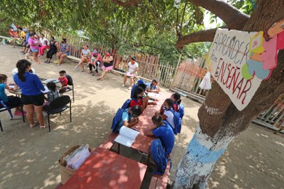 Génesis y Dennys Tola se reúnen con un grupo de niños debajo de un árbol.
