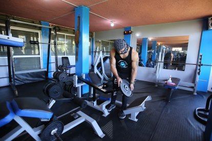 Luis Higuera alista las máquinas para la reapertura de su gimnasio en Amaguaña.