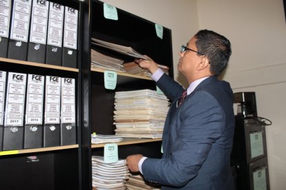 El fiscal César Peña revisa los archivos encontrados en la estantería de su despacho.