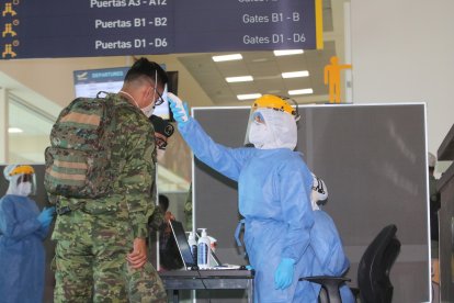 Personal del aeropuerto toma la temperatura de los pasajeros que llegan a la capital.