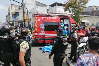 La víctima yace en el piso entre socorristas y policías que acudieron al lugar del crimen.