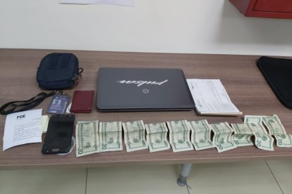 El talonario de citaciones, dinero, una laptop y otros objetos encontrados al detenido.