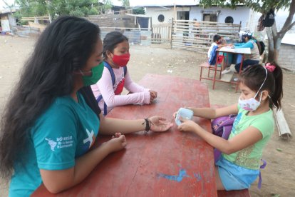 Con la ayuda de cartones numerados, Denisse Toala enseña la materia de matemáticas a tres pequeñas.