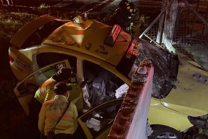 Los policías revisan el interior del taxi donde quedó el cadáver.