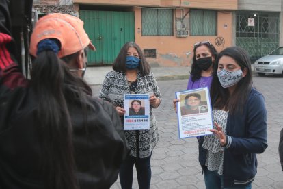 Carol Manzano entrega afiche de su madre desaparecida a los recicladores de basura para que la ayuden a encontrarla.