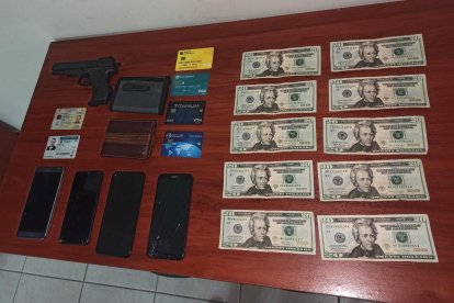 El arma, dinero y celulares encontrados a los cuatro detenidos.