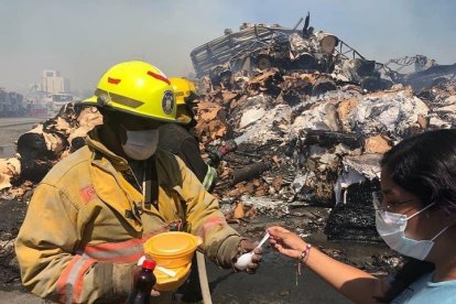 Su deseo de servir nunca se apaga. Voluntaria reparte comida a bombero que estuvo presente en incendio de una cartonera.