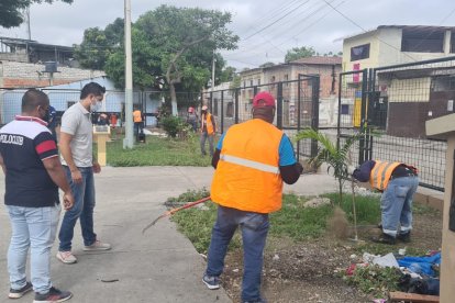 Moradores y policías limpian las aceras de un parque en el Guasmo sur de Guayaquil.