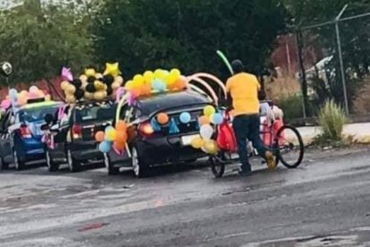 El padre de familia que lleva a su hijo en el triciclo que adornó para participar de la fiesta de fin de curso.