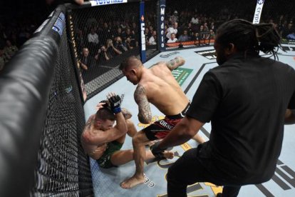 Conor McGregor (i) se defiende tras sufrir la rotura de su tibia izquierda.