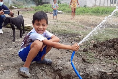 Un 'pelado' con rostro feliz riega la calle con una manguera, algo que no se veía por La Chontilla hace mucho tiempo.