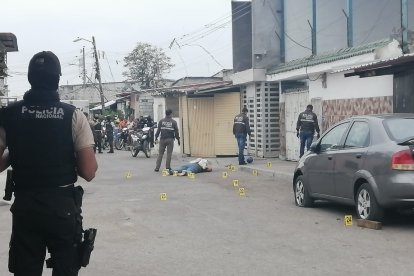 Un policía observa la escena del crimen, donde yace la víctima baleada.