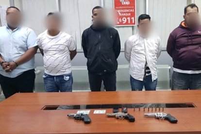 Los cinco sospechosos junto a las armas que portaban al momento del asalto.