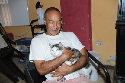 Héctor acaricia a Michuchi, el felino que llegó hasta su casa y desde entonces no se separan.