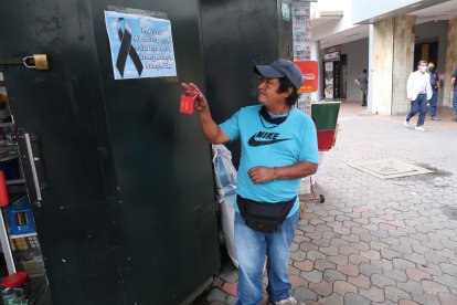 . Desconsolado, Segundo observa el afiche que amigos de la fallecida, Esmeralda Aguilar Bolaños (círculo), colocaron en la puerta de su negocio.