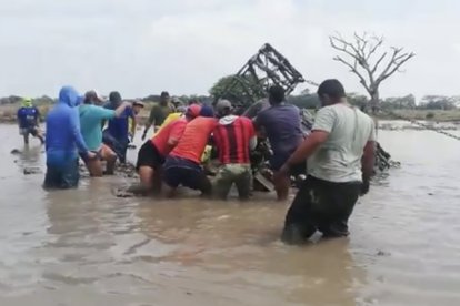 Personas tratan de remolcar el camión con ayuda de una cadena, para sacar a la víctima.