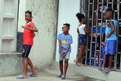 Un grupo de niños juega cerca de una tienda. Uno de ellos usa una pistola de juguete para divertirse.