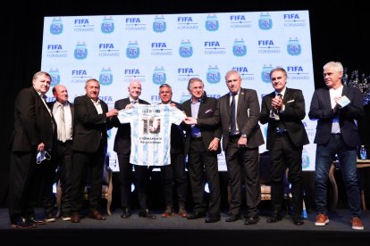 Claudio Tapia (5-i) posando sosteniendo una camiseta de la selección argentina dedicada al fallecido Diego Maradona con el presidente de la FIFA, Gianni Infantino